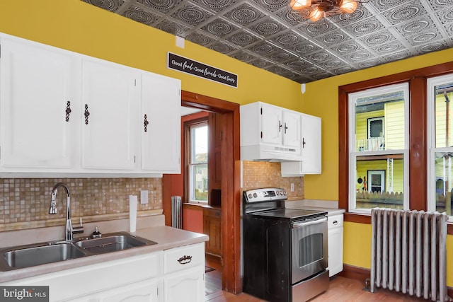 kitchen with stainless steel electric range oven, radiator, sink, and white cabinets