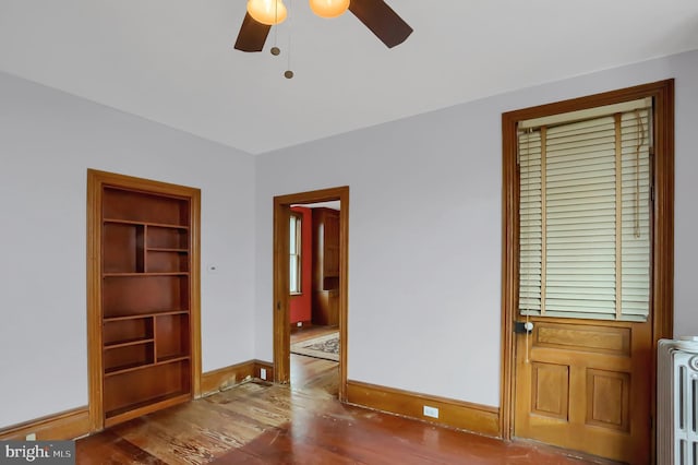 spare room featuring hardwood / wood-style flooring, built in features, and ceiling fan