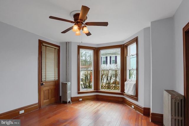 spare room featuring hardwood / wood-style flooring, radiator heating unit, and ceiling fan