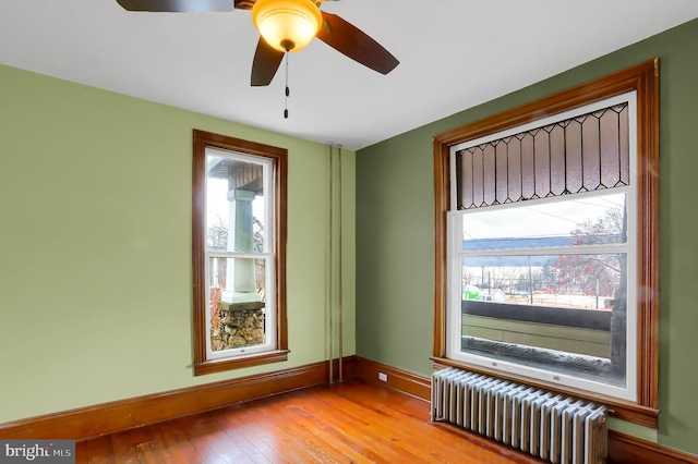 spare room featuring light hardwood / wood-style flooring, radiator heating unit, and a healthy amount of sunlight