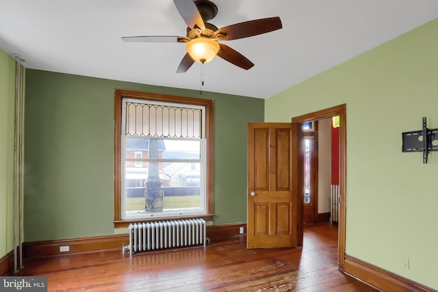 unfurnished room with hardwood / wood-style flooring, ceiling fan, and radiator heating unit