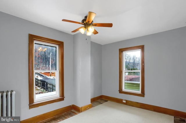 spare room featuring ceiling fan, wood-type flooring, and radiator