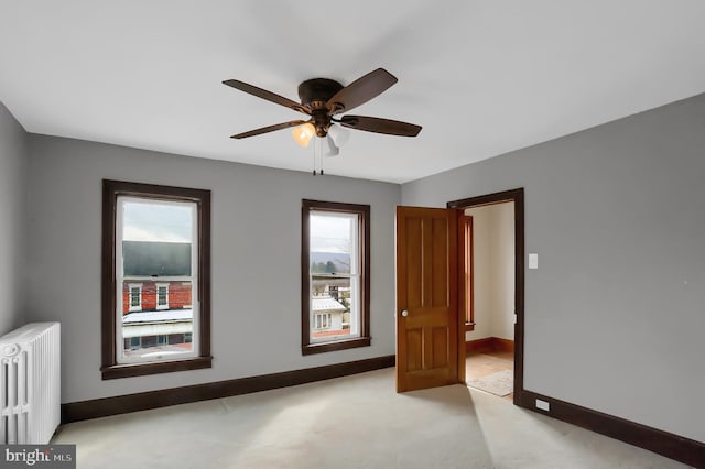 carpeted spare room with radiator heating unit and ceiling fan