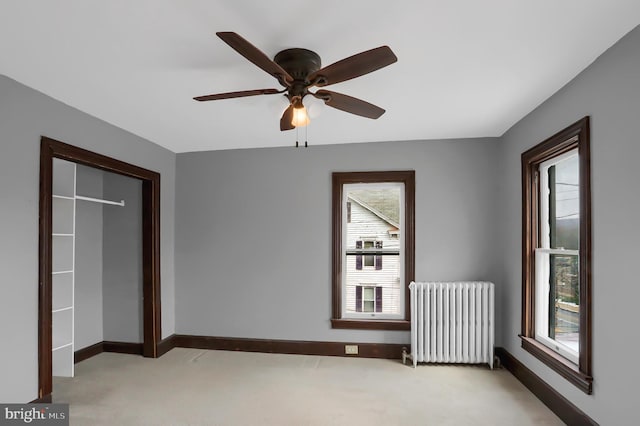 unfurnished bedroom with ceiling fan, radiator heating unit, and light carpet