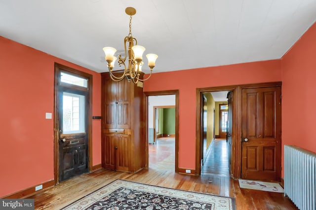 interior space featuring hardwood / wood-style flooring, radiator heating unit, and a notable chandelier