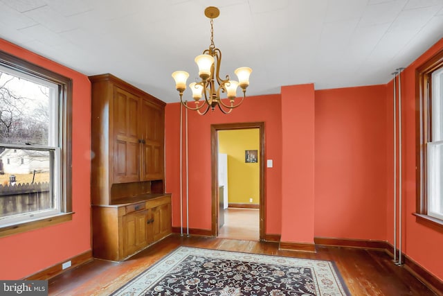 unfurnished dining area featuring hardwood / wood-style flooring and a notable chandelier