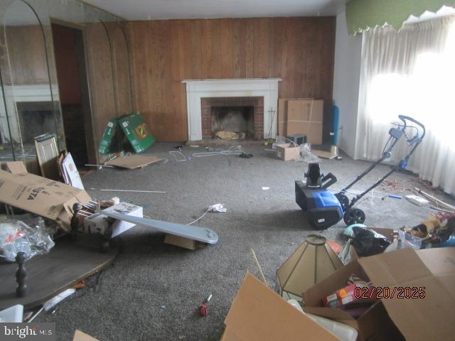 unfurnished living room with wood walls and a brick fireplace