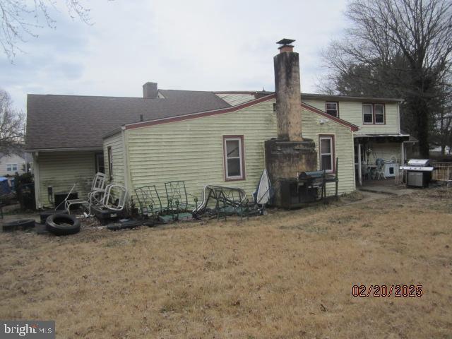 back of house featuring a yard and a chimney