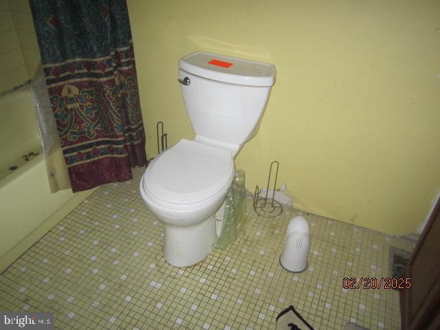 full bathroom featuring washtub / shower combination, tile patterned flooring, and toilet