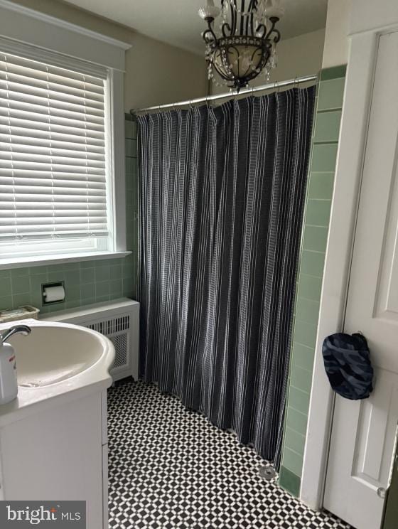 bathroom featuring vanity, a shower with shower curtain, tile walls, and a notable chandelier