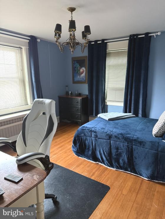 bedroom with an inviting chandelier and hardwood / wood-style flooring