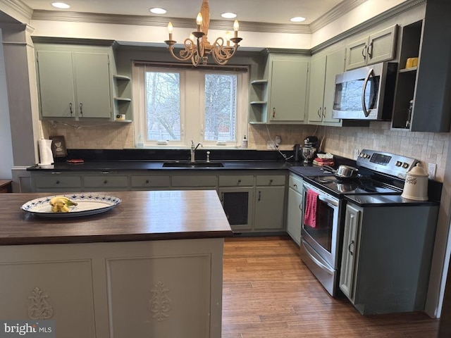 kitchen featuring appliances with stainless steel finishes, sink, a chandelier, hardwood / wood-style flooring, and crown molding