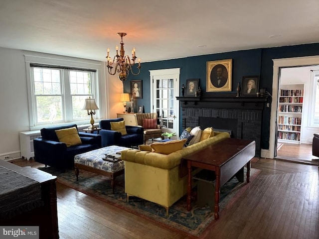 sitting room with dark hardwood / wood-style flooring, a brick fireplace, and a notable chandelier