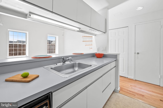 kitchen with light wood finished floors, recessed lighting, a sink, and white cabinets