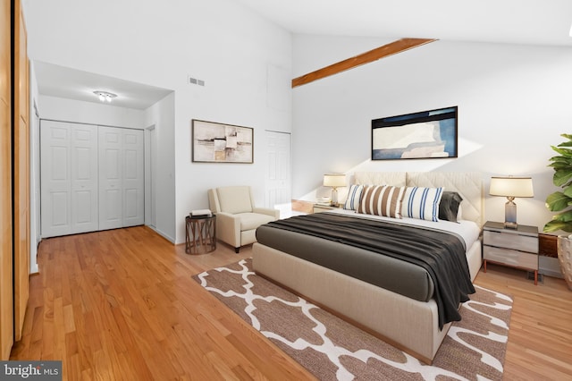 bedroom with high vaulted ceiling, visible vents, and wood finished floors