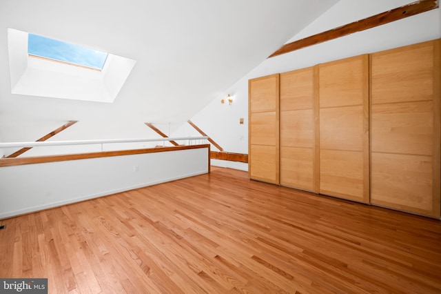 additional living space featuring lofted ceiling with skylight and light wood-style floors