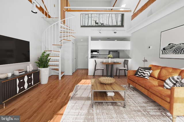 living room featuring a high ceiling, stairway, and wood finished floors