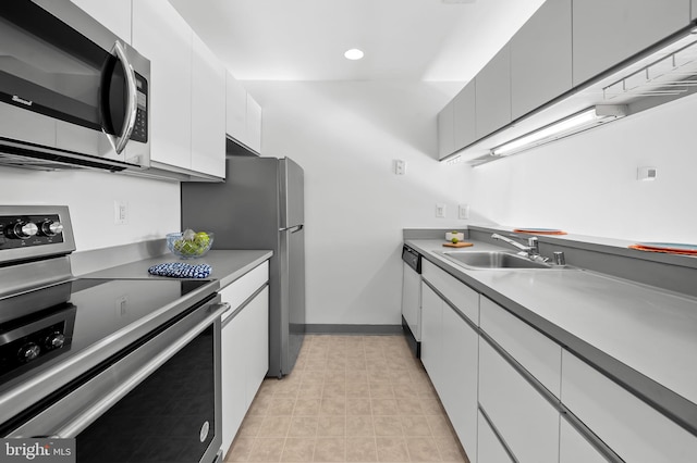 kitchen with appliances with stainless steel finishes, light countertops, white cabinets, and a sink