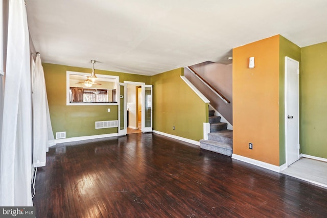 unfurnished living room featuring wood-type flooring, visible vents, baseboards, and stairs