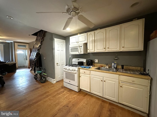 kitchen with sink, white appliances, light hardwood / wood-style flooring, and ceiling fan