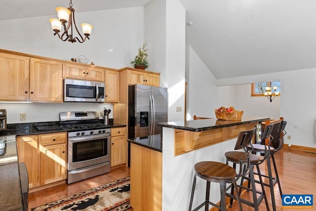 kitchen featuring a center island, hanging light fixtures, dark stone counters, stainless steel appliances, and light hardwood / wood-style floors