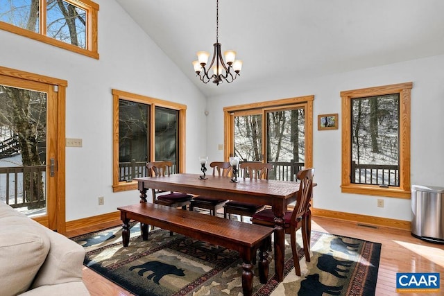 dining area featuring hardwood / wood-style floors, high vaulted ceiling, and a chandelier