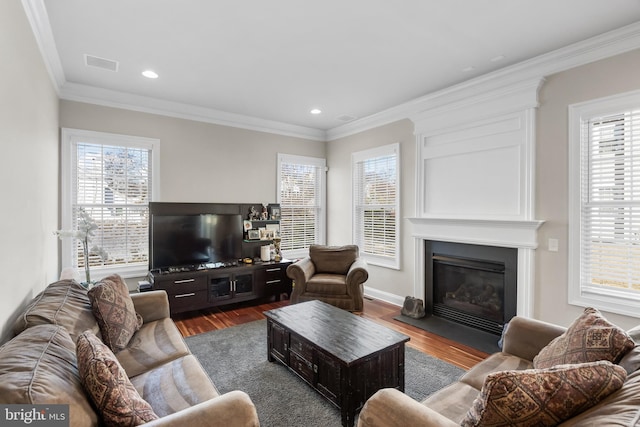 living room featuring recessed lighting, a fireplace, crown molding, and wood finished floors