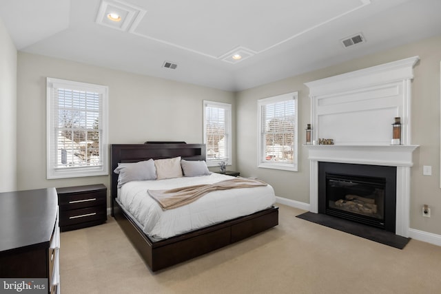 bedroom featuring light carpet, visible vents, a fireplace with flush hearth, and baseboards