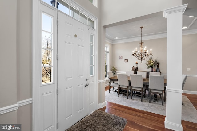 entrance foyer with baseboards, decorative columns, dark wood-style flooring, ornamental molding, and a chandelier