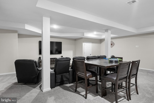 carpeted dining room with a raised ceiling, baseboards, and visible vents