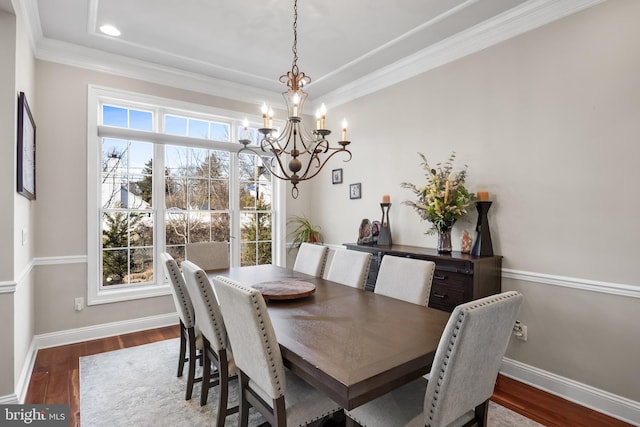 dining area featuring a notable chandelier, ornamental molding, baseboards, and wood finished floors