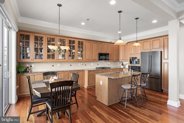 kitchen featuring a kitchen bar, black appliances, an island with sink, light stone counters, and dark wood-style flooring