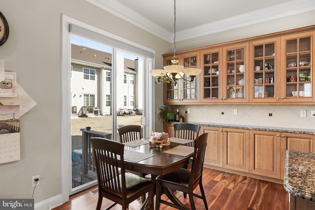 dining room featuring baseboards, dark wood-type flooring, a chandelier, and crown molding