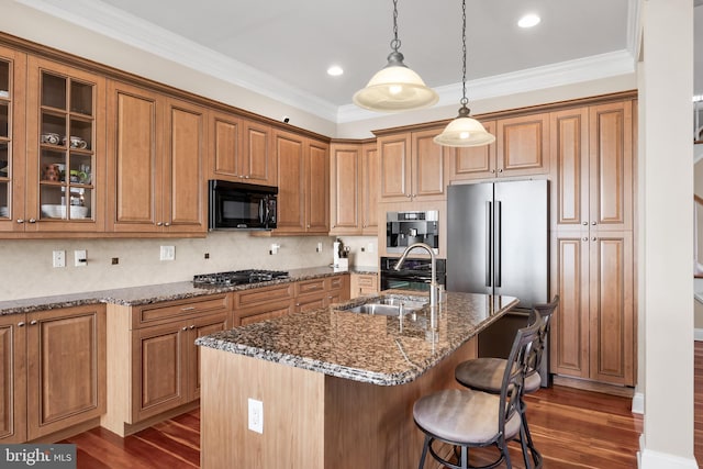 kitchen featuring a sink, dark stone counters, appliances with stainless steel finishes, and a breakfast bar