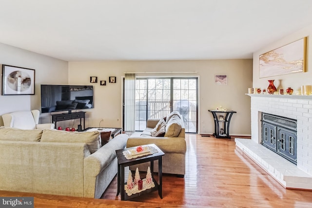 living area with a brick fireplace and wood finished floors