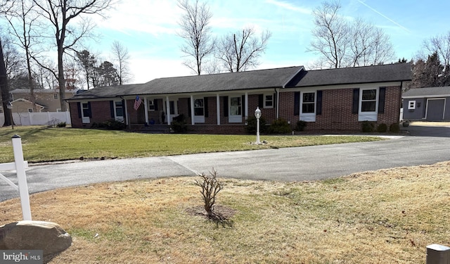 ranch-style house with a front yard, brick siding, and fence