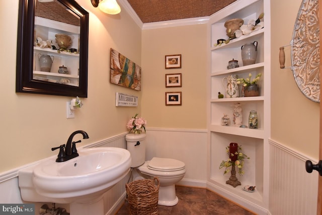 half bath featuring toilet, built in shelves, ornamental molding, and wainscoting