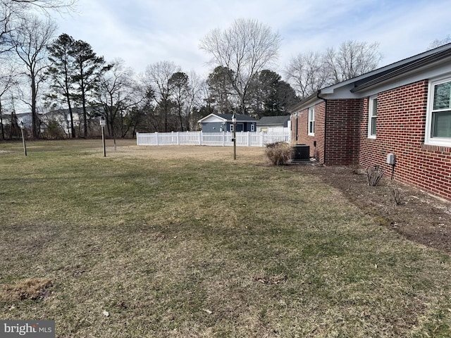 view of yard with central AC and fence