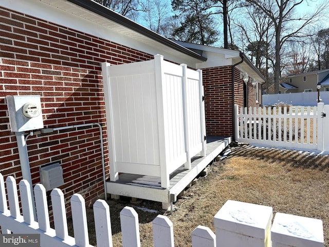 view of side of home with brick siding and fence