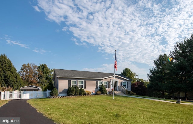 ranch-style home featuring a garage, an outdoor structure, and a front lawn