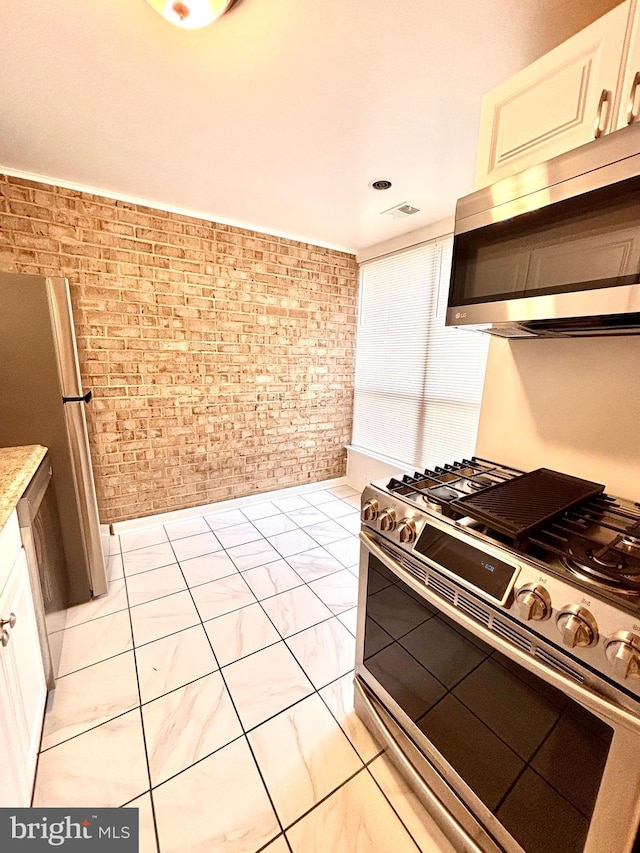 kitchen with brick wall and appliances with stainless steel finishes