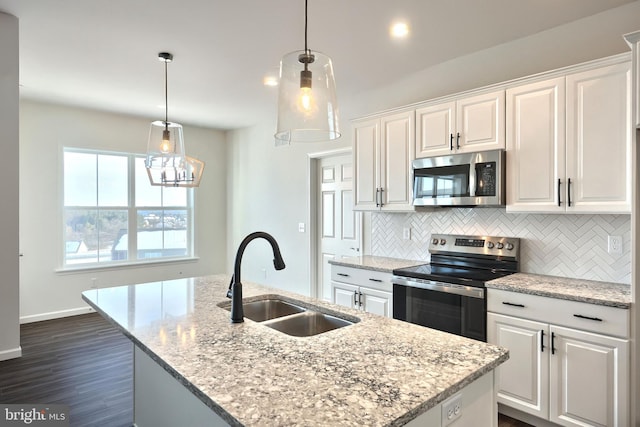 kitchen featuring stainless steel appliances, a kitchen island with sink, white cabinetry, and a sink