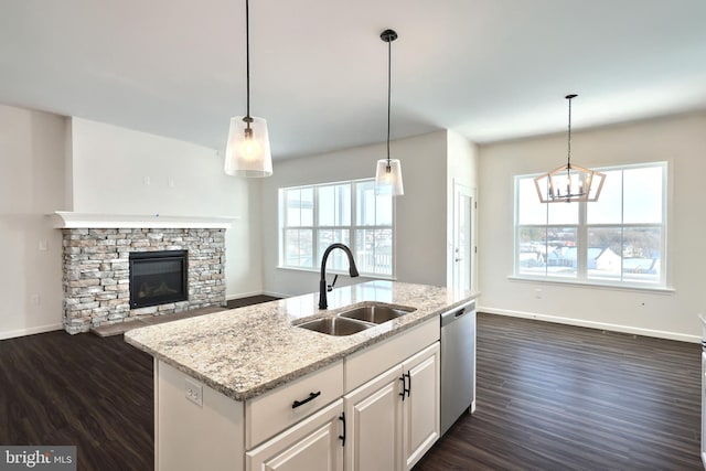 kitchen with stainless steel dishwasher, open floor plan, a kitchen island with sink, white cabinets, and a sink