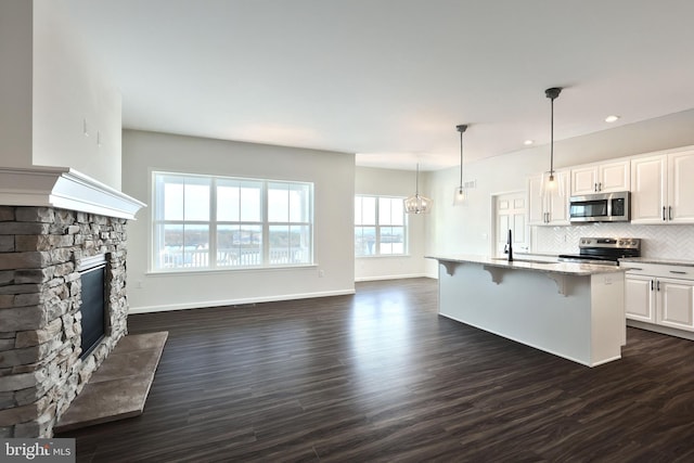 kitchen with stainless steel appliances, pendant lighting, white cabinetry, and a kitchen breakfast bar