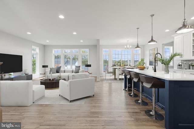 living room featuring sink, light hardwood / wood-style floors, and a notable chandelier