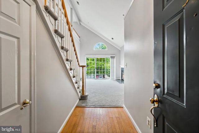 entrance foyer with stairway, high vaulted ceiling, baseboards, and hardwood / wood-style flooring