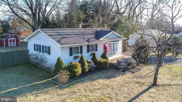 view of front of home with a front yard, an outdoor structure, fence, and a storage unit