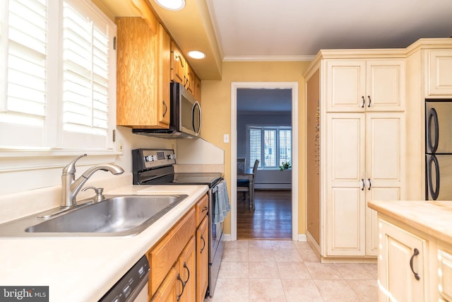 kitchen featuring light countertops, appliances with stainless steel finishes, a sink, and crown molding