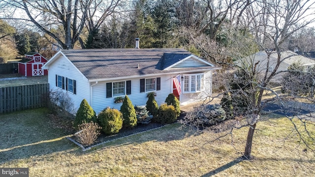 ranch-style home featuring fence, a storage unit, a front lawn, and an outbuilding