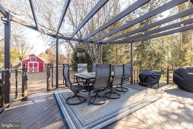 wooden terrace featuring grilling area, an outbuilding, outdoor dining area, and a shed